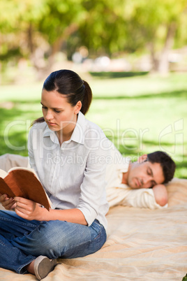 Woman reading while her husband is sleeping