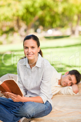 Woman reading while her husband is sleeping