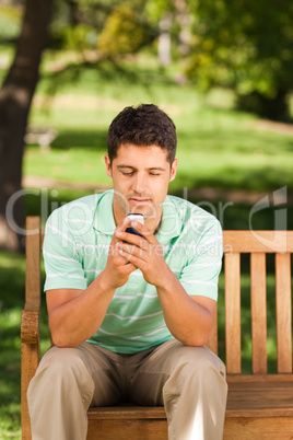 Man with his phone on the bench