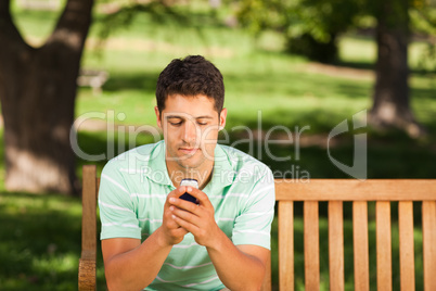 Man with his phone on the bench