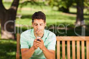 Man with his phone on the bench