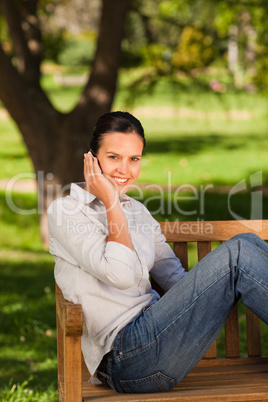 Young beautiful woman phoning on the bench