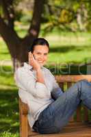 Young beautiful woman phoning on the bench