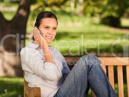 Young beautiful woman phoning on the bench