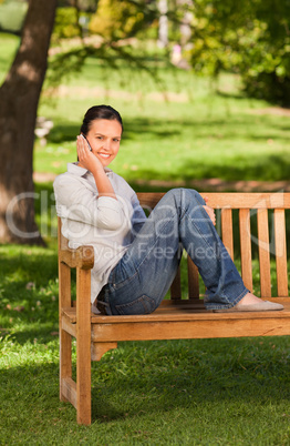 Young beautiful woman phoning on the bench