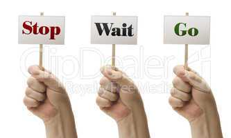 Three Signs In Fists Saying Stop, Wait and Go