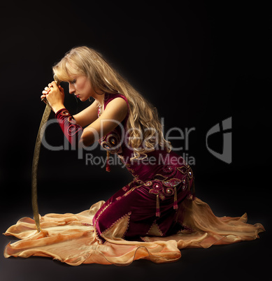 Sadness woman in arabian costume sit with saber