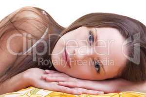 Young woman lay on color pillow and look at you