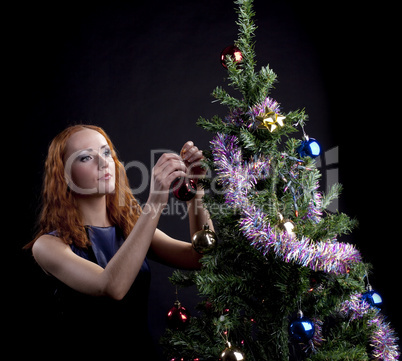 Young red woman decorate new year tree