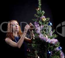 Young red woman decorate new year tree