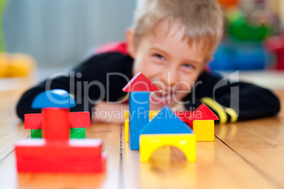 Fröhlicher kleiner Junge spielt mit bunten Holzbausteinen
