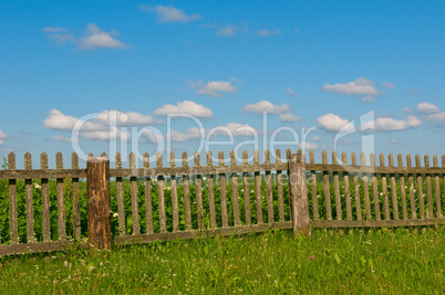 Blue sky, green grass and fence