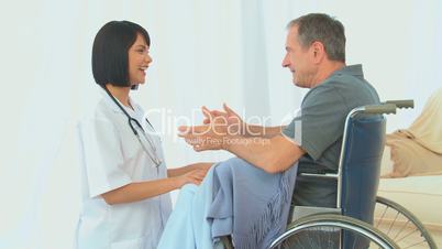 Ärztin im Gespräch mit einem Mann im Rollstuhl