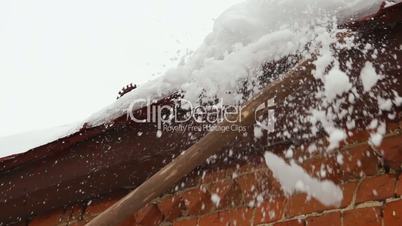 Cleaning snow and ice from roof cornice - countryside house