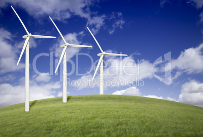 Three Wind Turbines Over Grass Field and Blue Sky