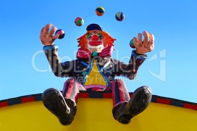 Clown beim Jonglieren mit Bällen sitzend auf einem Dach