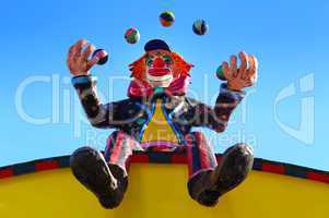 Clown beim Jonglieren mit Bällen sitzend auf einem Dach