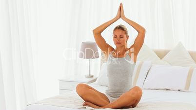 Frau macht Yogaübungen auf einem Bett