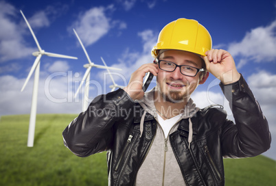 Hard Hat Wearing Engineer on Phone with Turbines Behind