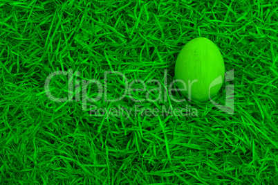 Green painted easter egg in a green nest