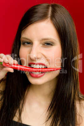 Chili pepper - portrait young woman bite red spicy