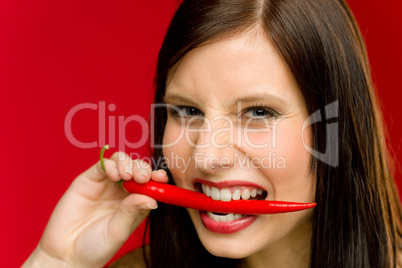 Chili pepper - portrait young woman bite red spicy