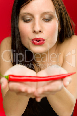 Chili pepper - portrait young woman blow on red hot