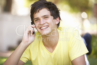 Teenage Boy Laying In Park Using Mobile Phone