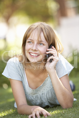 Teenage Girl Laying In Park Using Mobile Phone