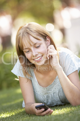 Teenage Girl Laying In Park Using Mobile Phone