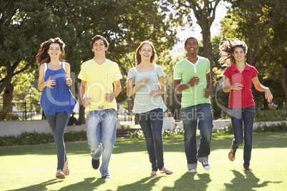 Group Of Teenagers Running Through Park