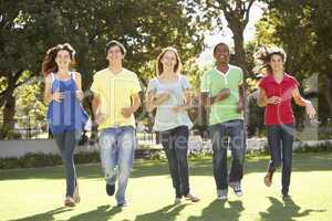 Group Of Teenagers Running Through Park