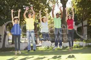 Group Of Teenagers Jumping In Air In Park