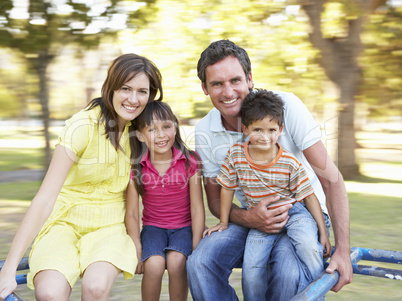 Family Riding On Roundabout In Park