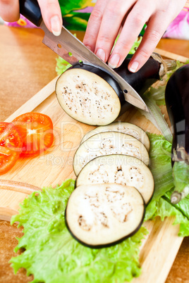 Woman's hands cutting aubergine eggplant