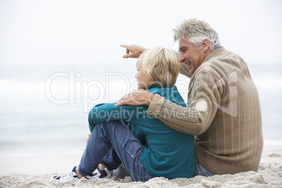 Grandfather And Son Sitting On Winter Beach Together