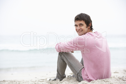 Young Man On Holiday Sitting On Winter Beach