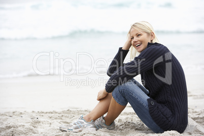 Young Woman On Holiday Sitting On Winter Beach