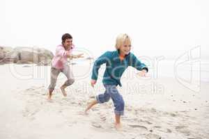 Father Chasing Son Along Winter Beach