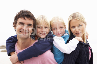 Young Family Sitting On Winter Beach