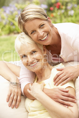 Senior Woman And Adult Daughter Relaxing In Garden