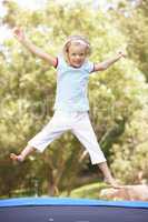 Young Girl Jumping On Trampoline In Garden