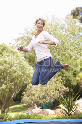 Woman Jumping On Trampoline In Garden