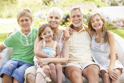 Grandparents And Grandchildren Relaxing In Garden