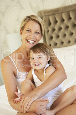 Mother And Daughter Relaxing In Bedroom