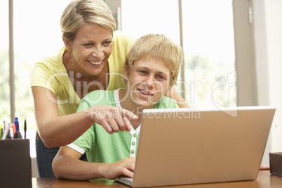 Mother And Teenage Son Using Laptop At Home