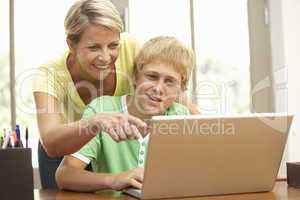 Mother And Teenage Son Using Laptop At Home