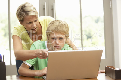 Angry Mother And Teenage Son Using Laptop At Home