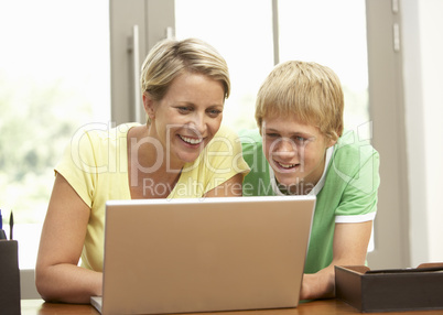 Mother And Teenage Son Using Laptop At Home