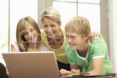 Mother And Teenage Children Using Laptop At Home